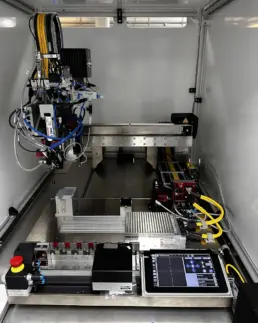 Foto zeigt einen marc0 Portal Roboter von marco, mit einem Dosierkopf und verschiedenen Kabeln in einem Gehäuse.