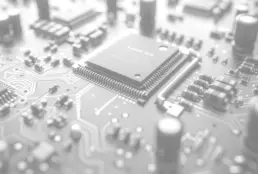 The image is a close-up of a computer circuit board with a microchip on it. The microchip is black and has a silver border. The circuit board is covered in many wires and connections, showcasing the intricate details of the electronic components.