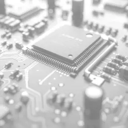 The image is a close-up of a computer circuit board with a microchip on it. The microchip is black and has a silver border. The circuit board is covered in many wires and connections, showcasing the intricate details of the electronic components.