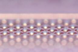 Enlarged side view of multiple solder paste dots arranged in parallel rows of uniform size on a surface.