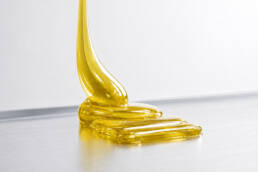 A yellowish, transparent, high-viscosity material on a metallic surface