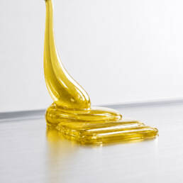 A yellowish, transparent, high-viscosity material on a metallic surface