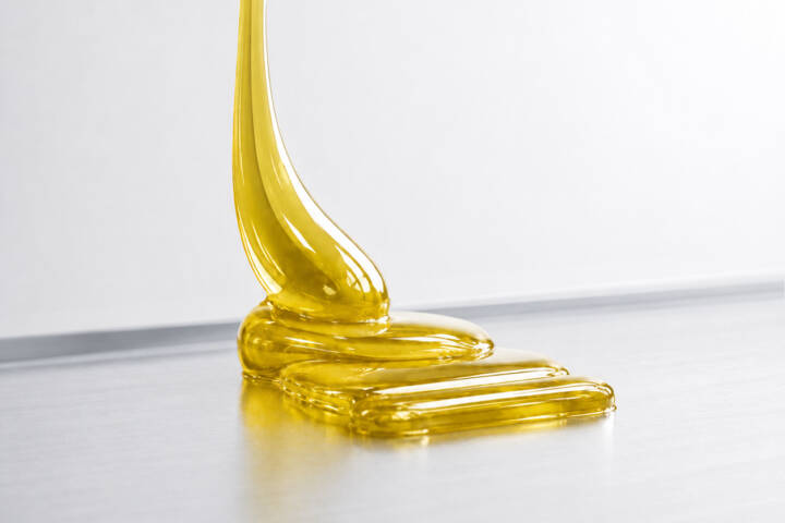 A yellowish, transparent, high-viscosity material on a metallic surface